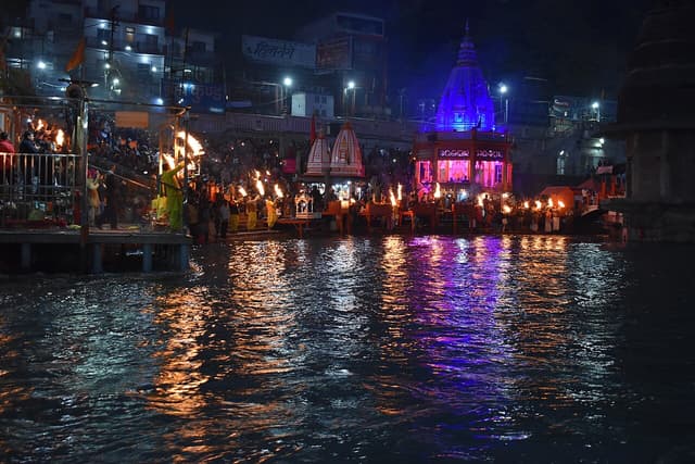 Ganga aarti lamps reflected in the river at Har Ki Pauri at night